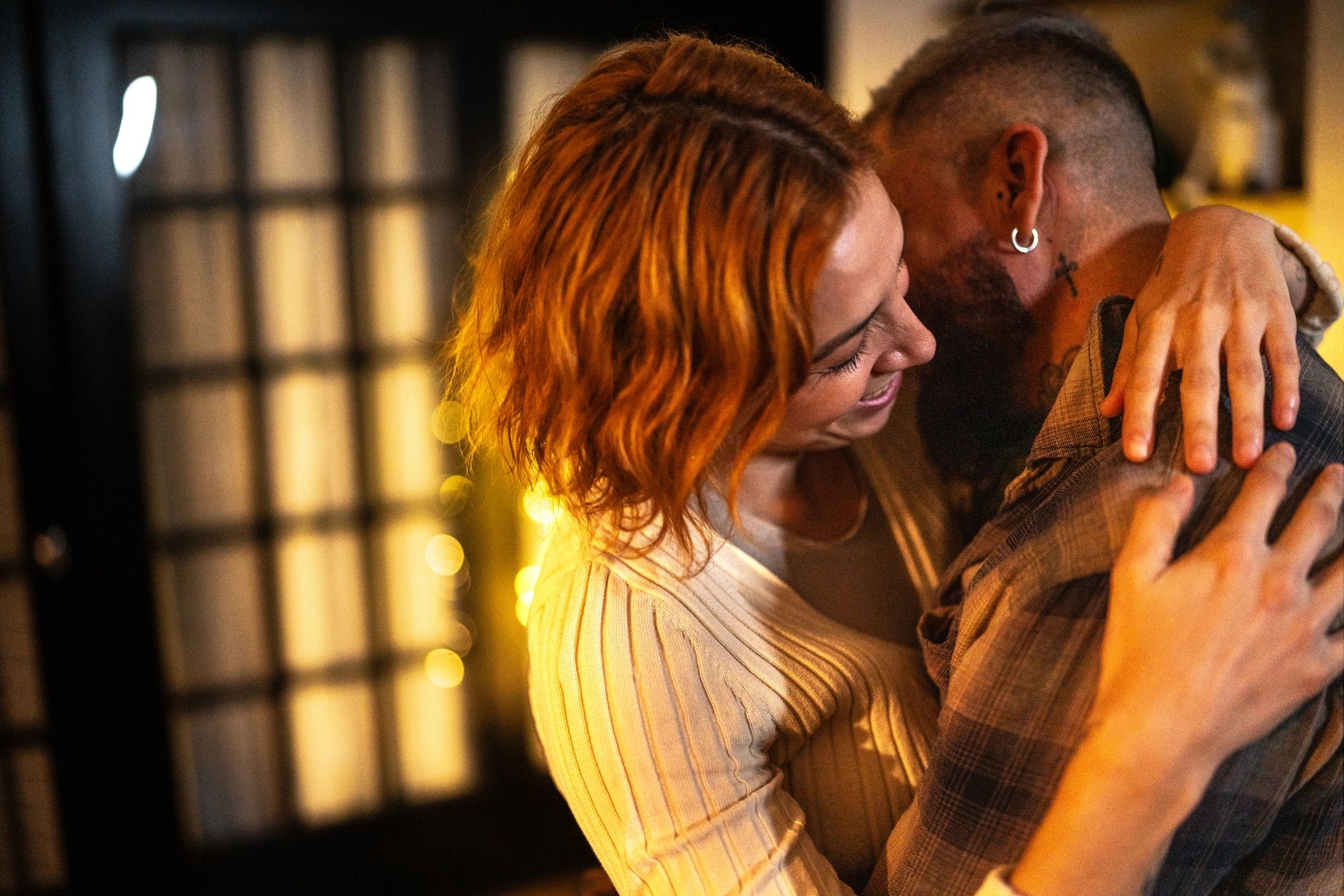 Tasteful couple embrace in a softly lit interior, representing comfort and connection